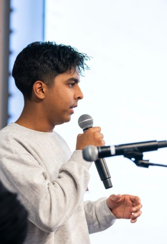 Rishi speaking into a microphone at an event